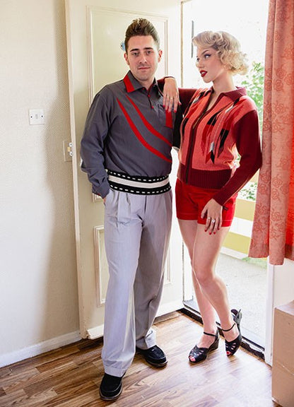 Two people posing indoors, one in a gray and red outfit and the other in a red dress with black accents.