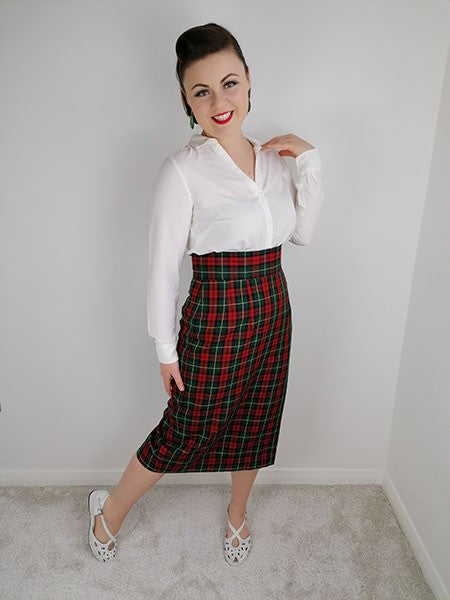 Woman wearing a white blouse and red plaid skirt against a plain background