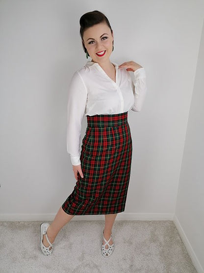 Woman wearing a white blouse and red plaid skirt against a plain background