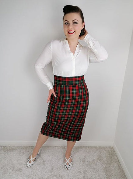 Woman wearing a white blouse and red plaid skirt against a plain background
