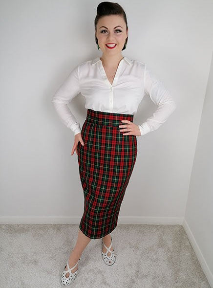 Woman wearing a white blouse and red plaid skirt against a plain background