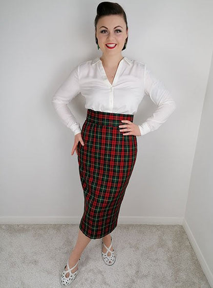 Woman wearing a white blouse and red plaid skirt against a plain background