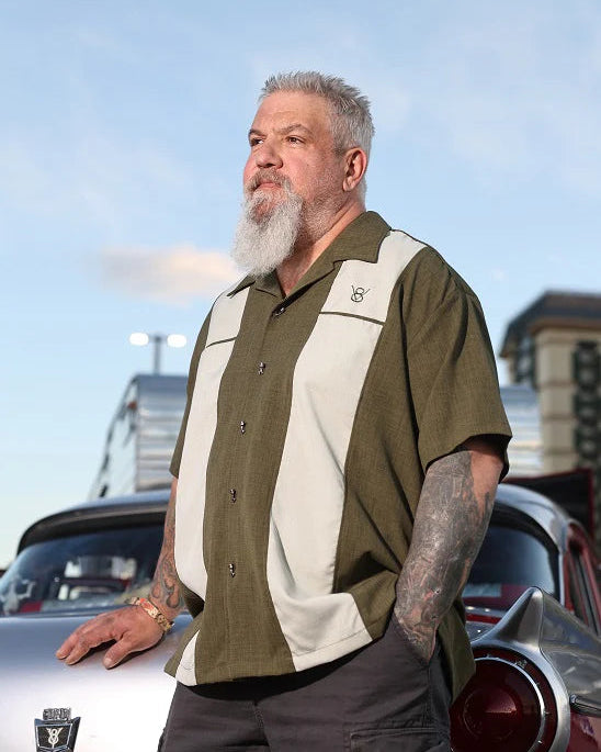 Man with a beard and tattoos standing next to a classic car