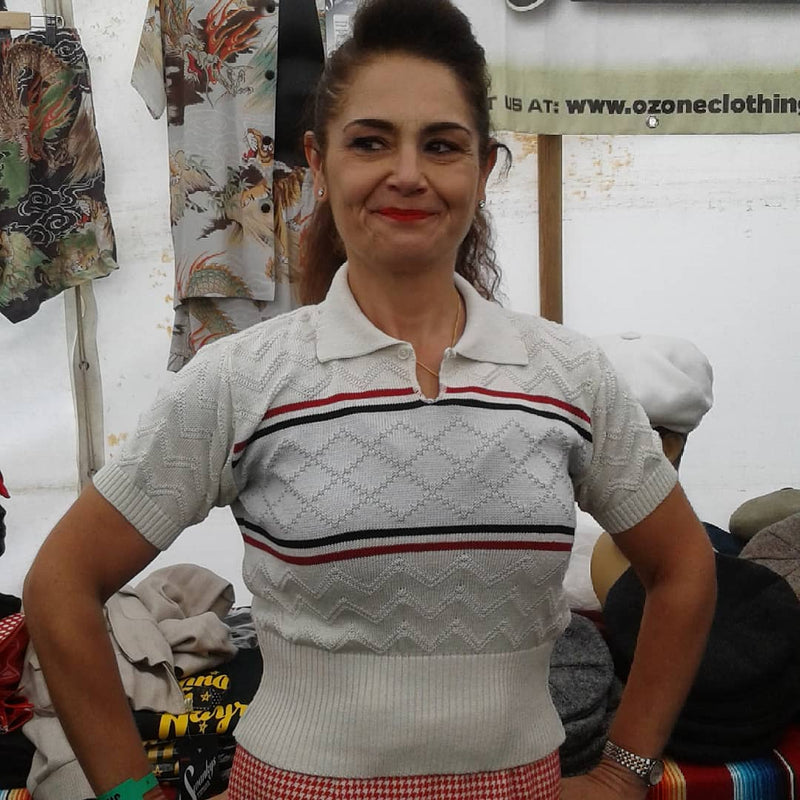 Woman wearing a white sweater with red and blue stripes in a clothing store.