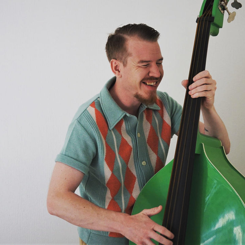 Man playing a green bass guitar against a plain background
