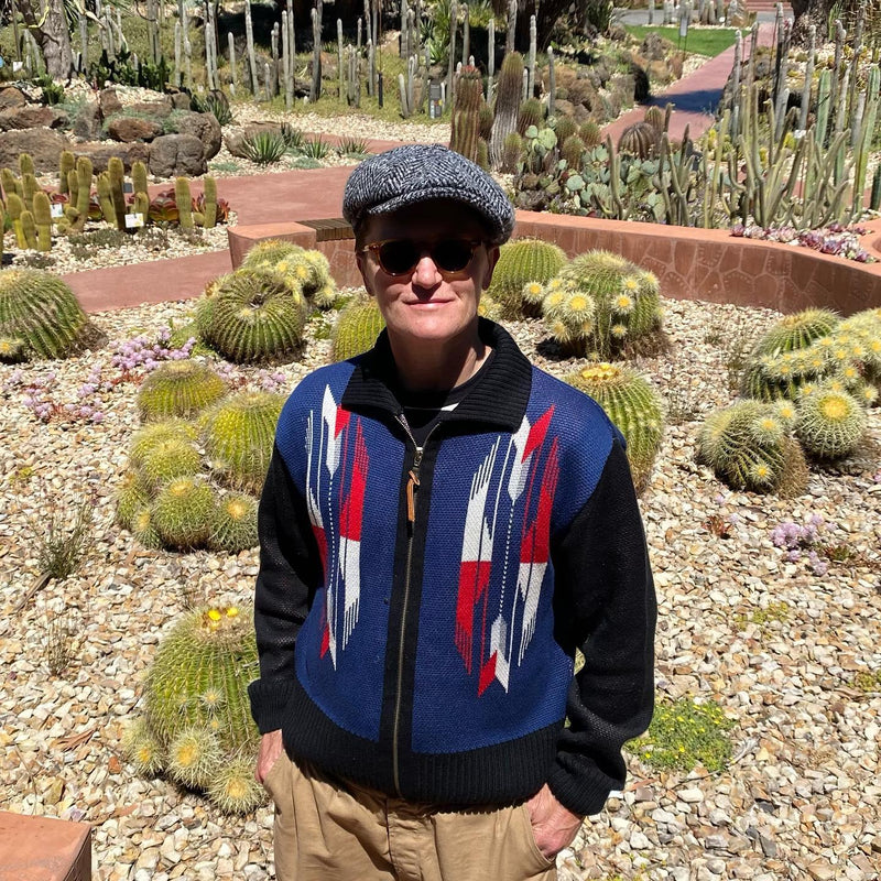 Person wearing a colorful sweater with cacti in the background