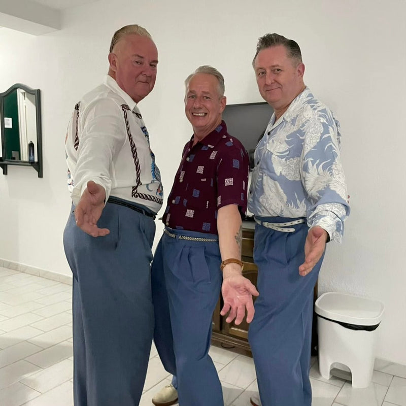 Three men posing together in a tiled white room