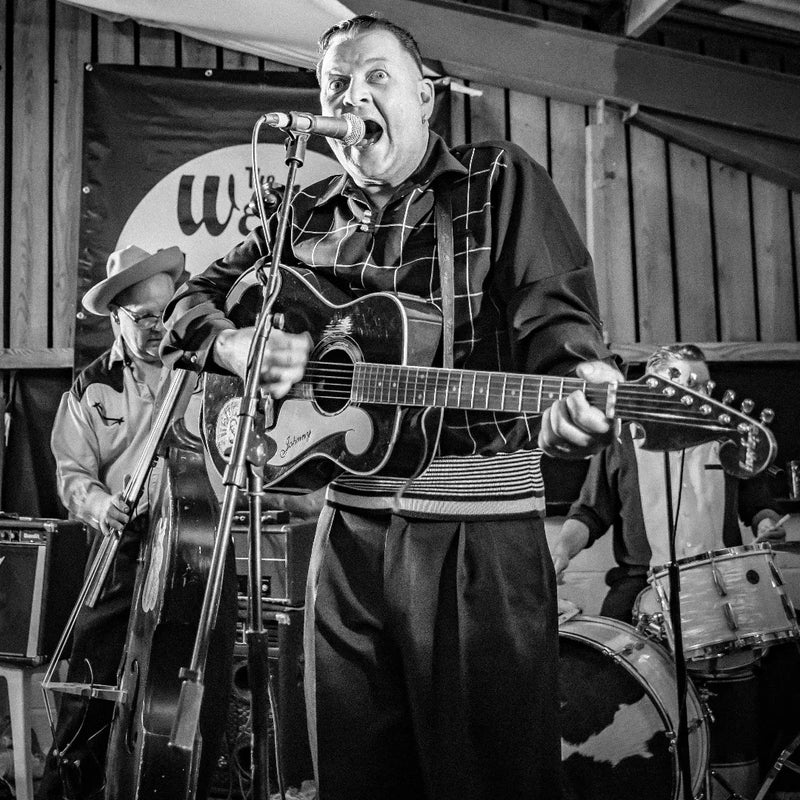 Black and white photo of a band performing with a microphone and guitar.