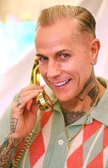 Man with tattoos holding a gold phone against a colorful background