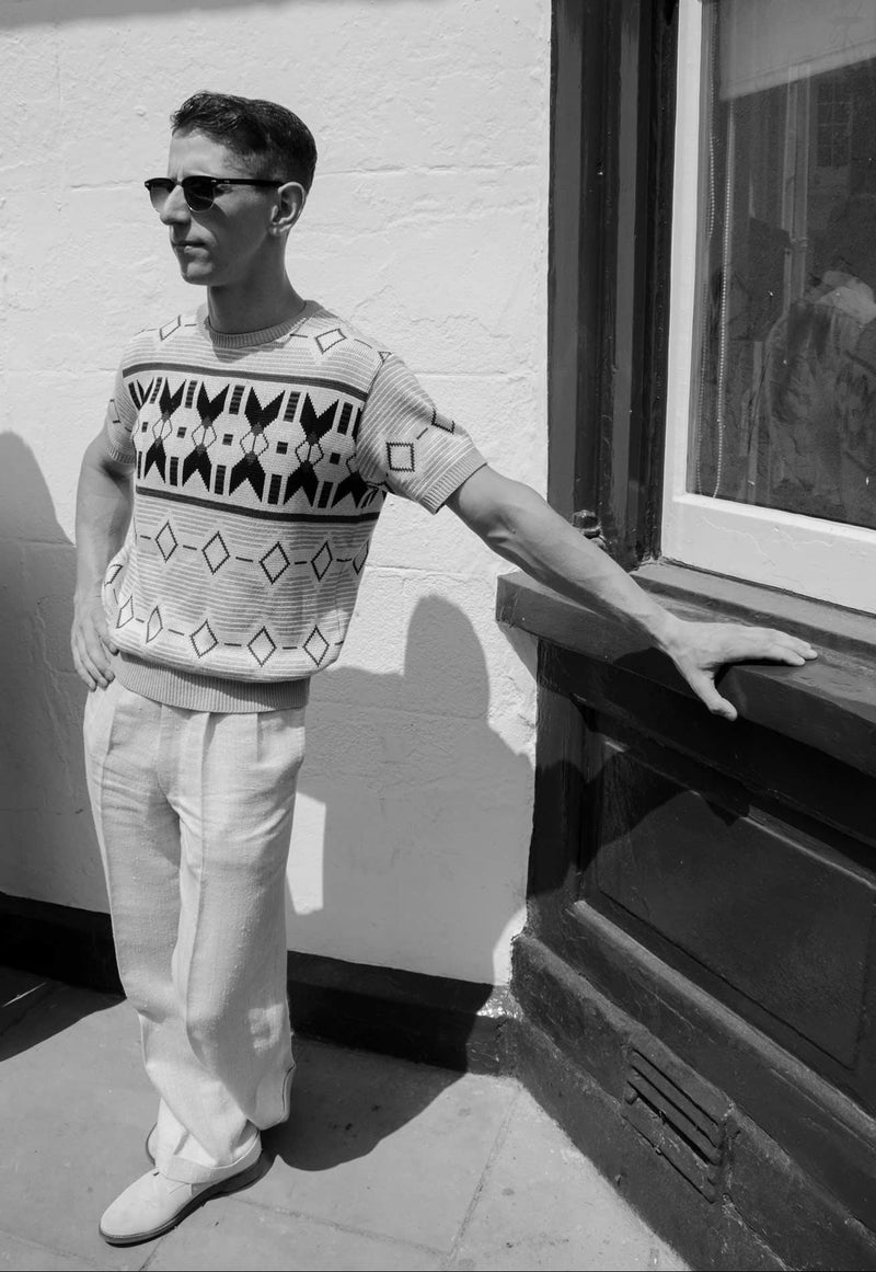 Man wearing a patterned shirt and sunglasses standing on a rooftop.
